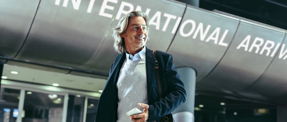 Mann mit Handy vorm Landeterminal am Flughafen