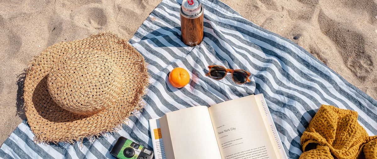 Beach towel with sun hat and book