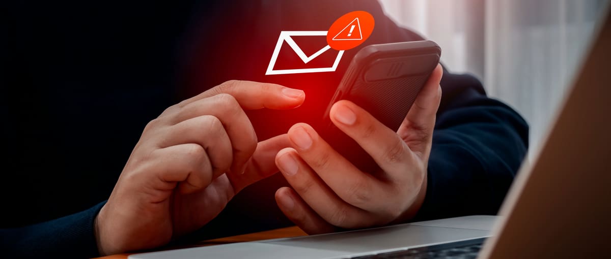 Un homme utilise son téléphone mobile et reçoit un e-mail louche