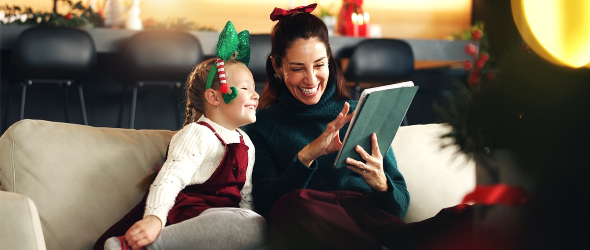Donna con bambino tiene in mano un tablet con motivi natalizi